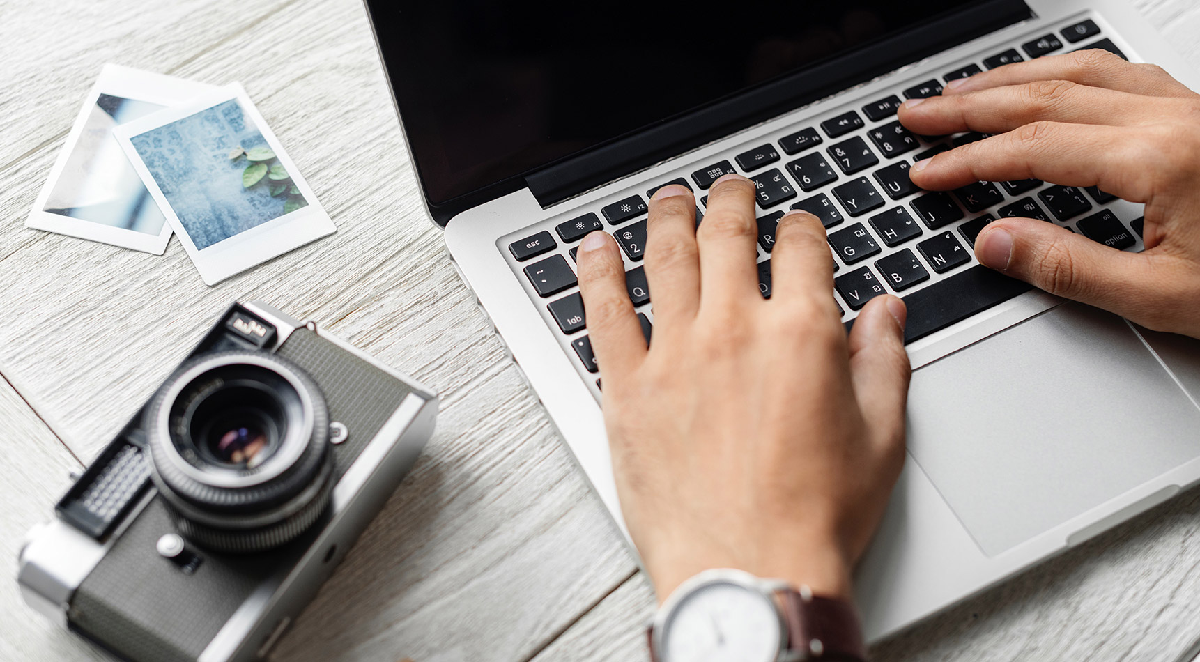 typing on a macbook with a camera | necessary website design brisbane